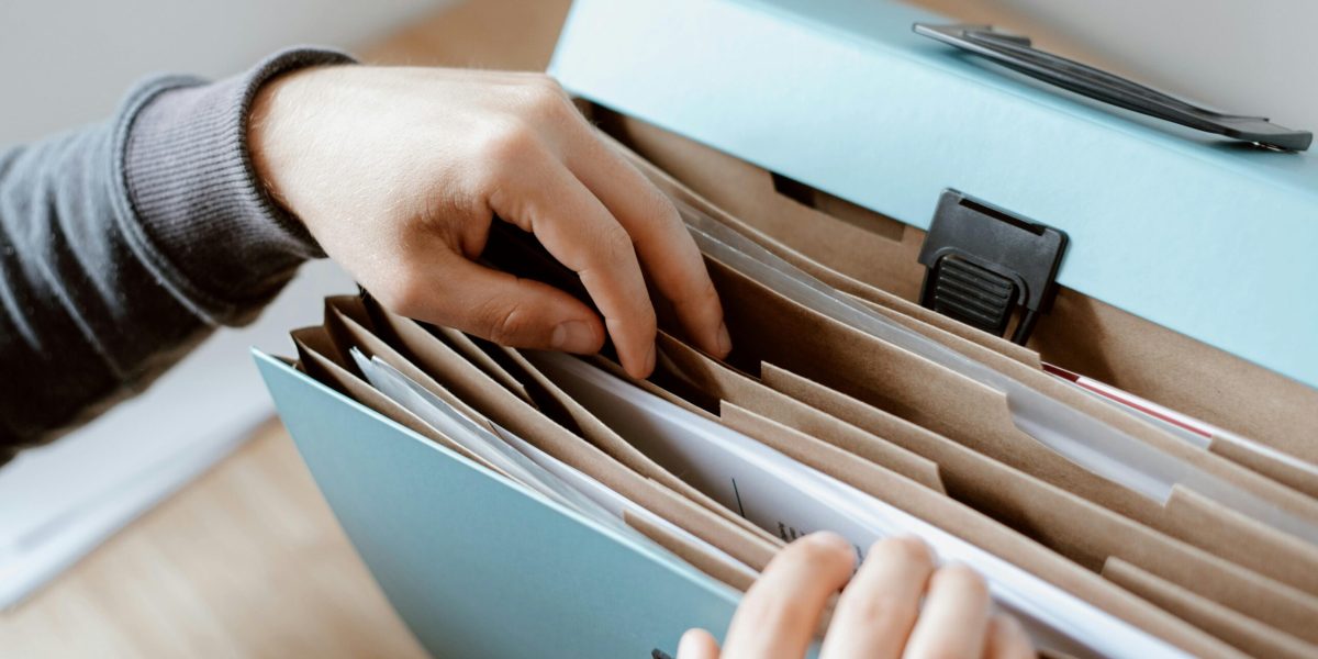 Close-up of hands organizing papers in a blue folder, ideal for business and office concepts.